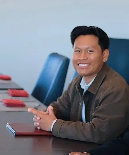 Brave View co-founder Randy smiling at a conference table in a brown jacket
