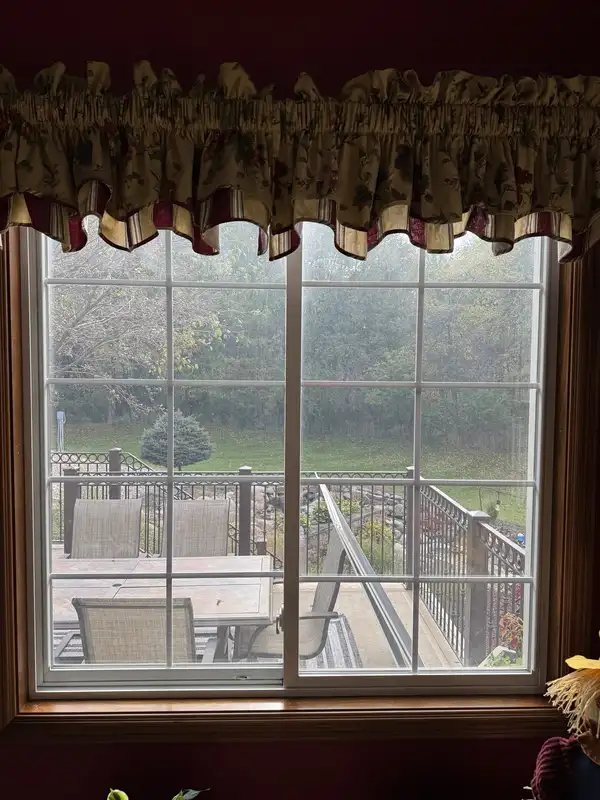Roanoke sliding glass door before cleaning, glass hazy under a floral valance